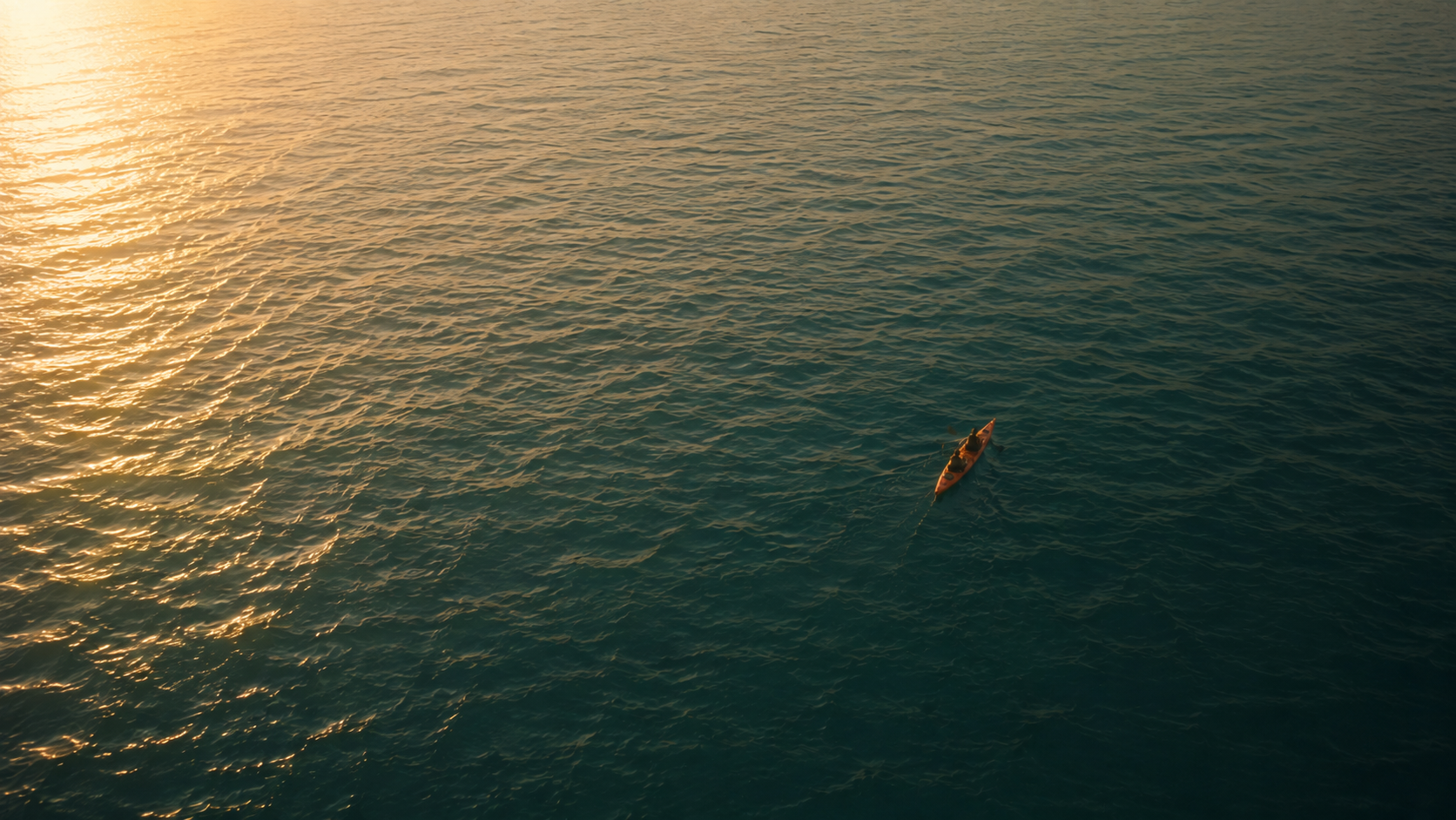 Een kajak vaart op rustig water, gezien vanuit de lucht bij zacht zonlicht